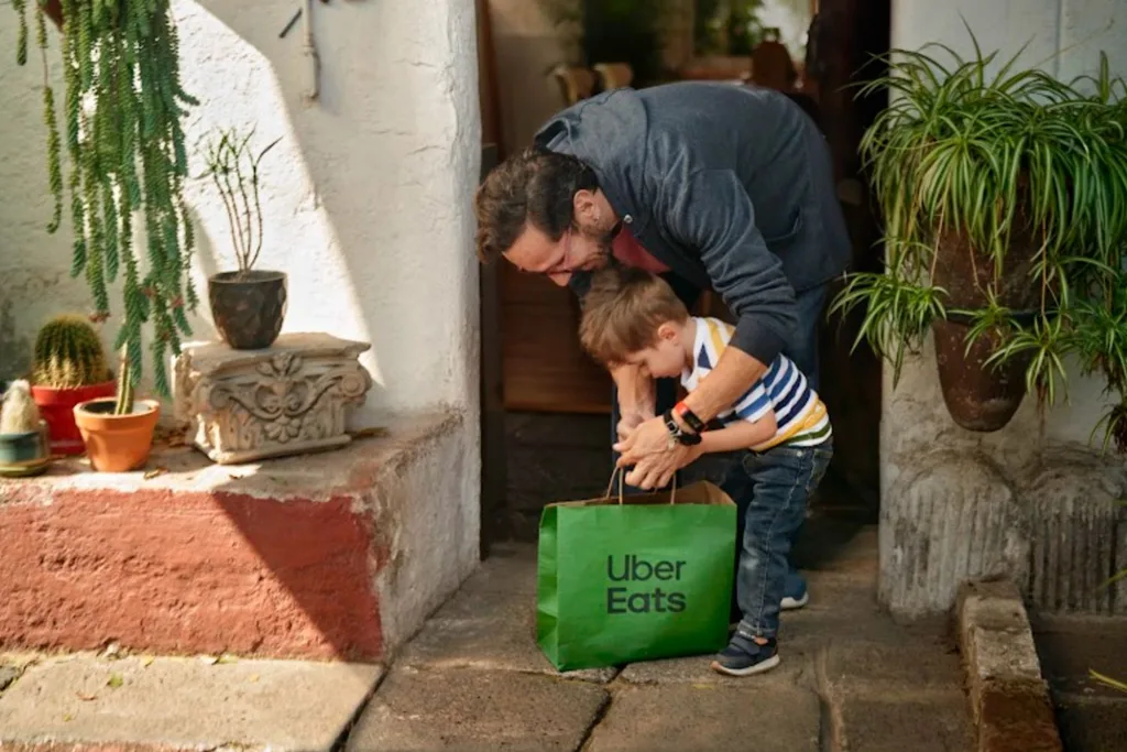 Man and little boy collecting Uber delivery from floor outside home