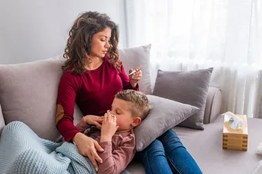 Mum and little boy blowing his nose on couch