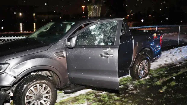Photo of a black car in a crash with windows smashed. 