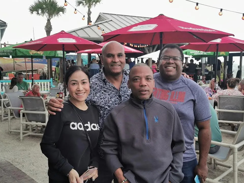 Three men standing next to woman and all smilling at camera. 
