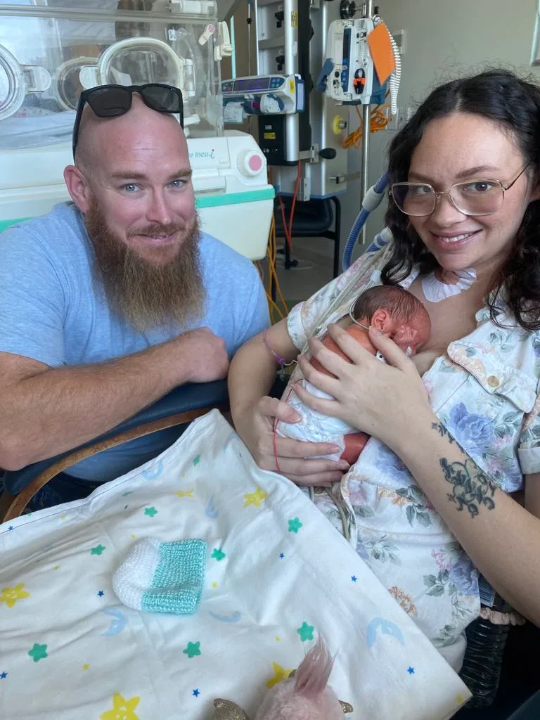 Image of husband and wife with newborn in hospital