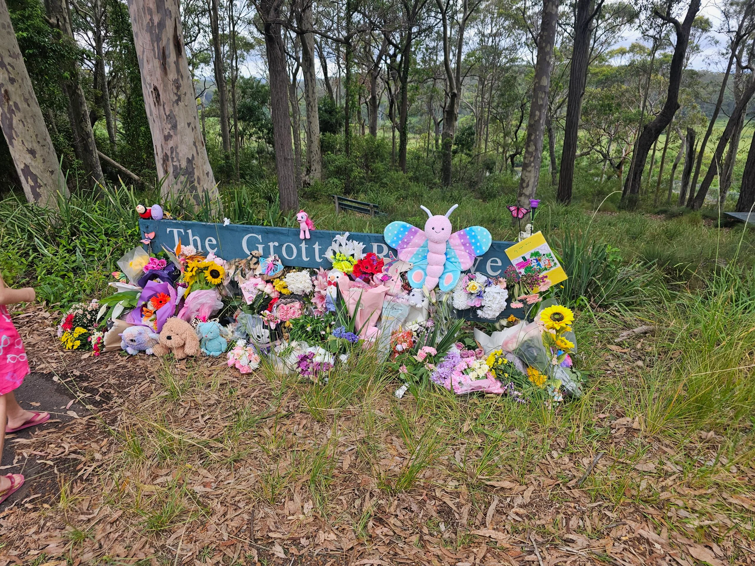 sign that reads 'the grotto' covered in flowers and toys