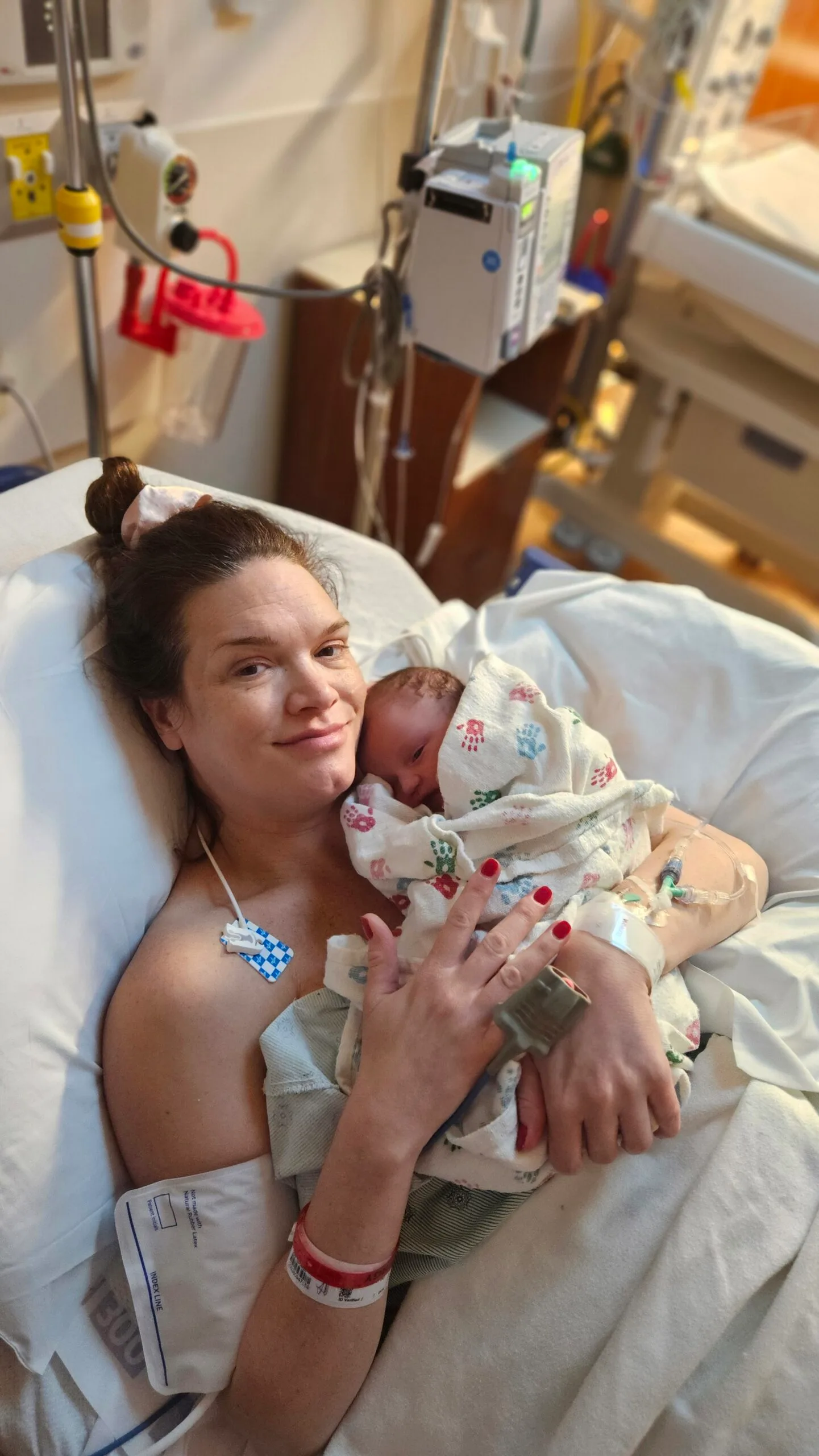 Woman on hospital bed holding newborn baby to the chest. 
