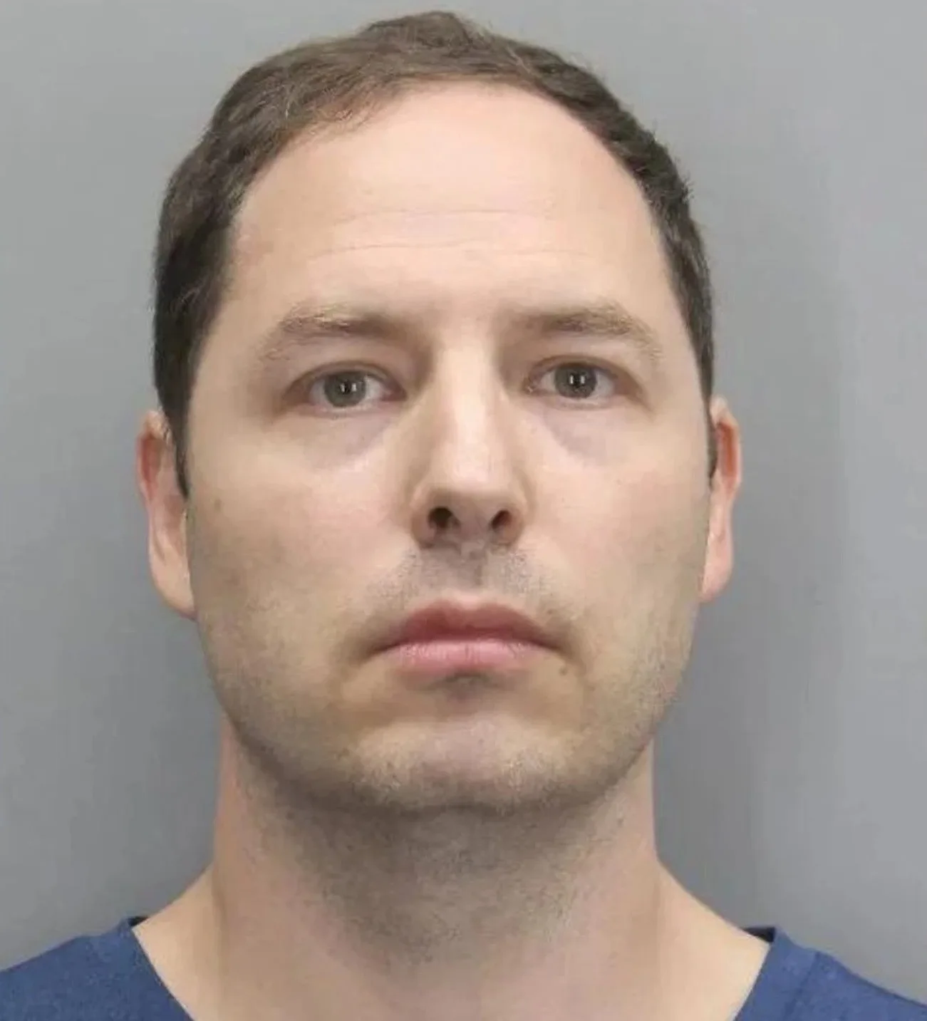 Mugshot of man wearing blue shirt.
