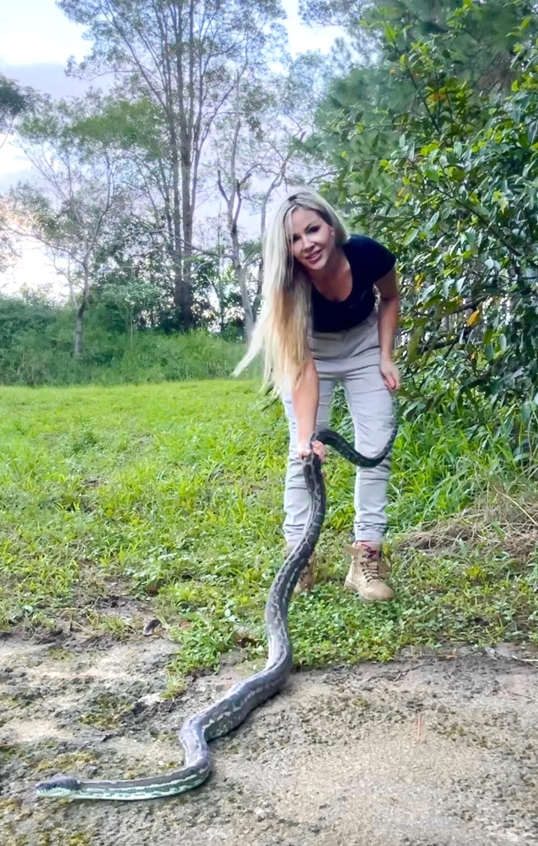 woman ctaching snake outside