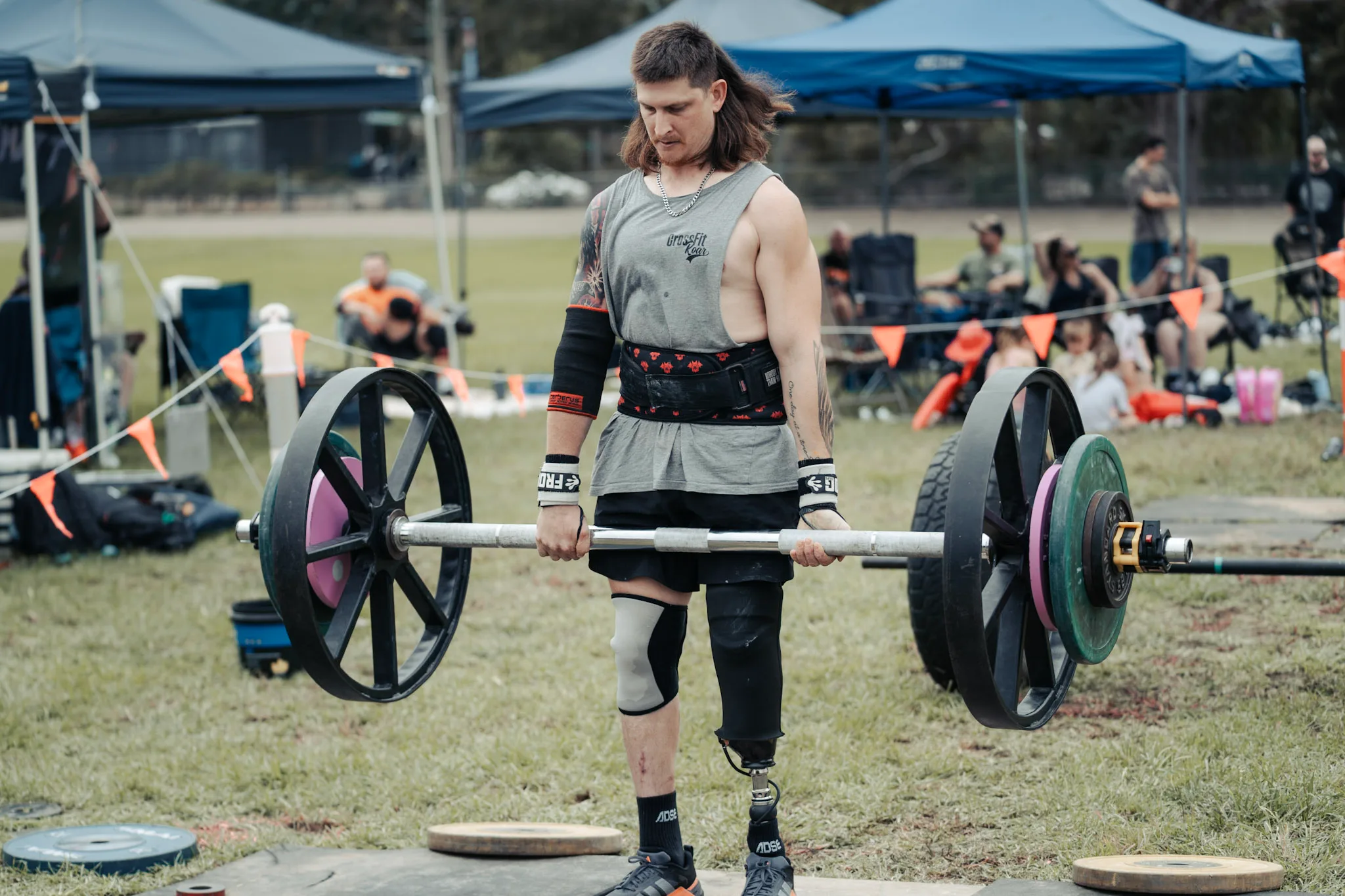 Man with prosthetic leg holding up barbell. 