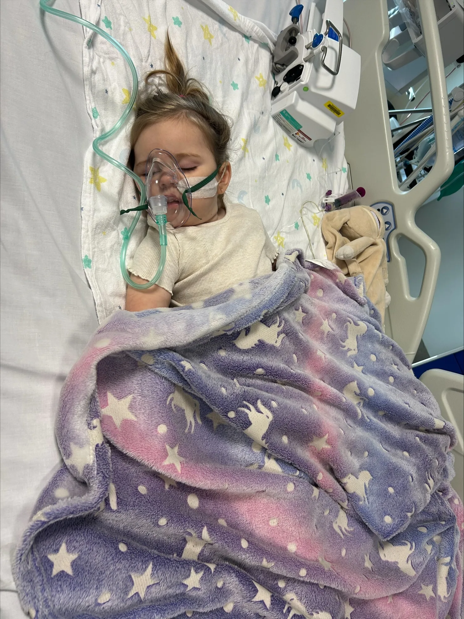 baby with an oxygen mask sleeping on hospital bed. 