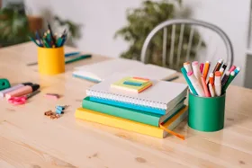 School desk with school supplies against a white wall