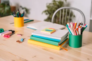 School desk with school supplies against a white wall