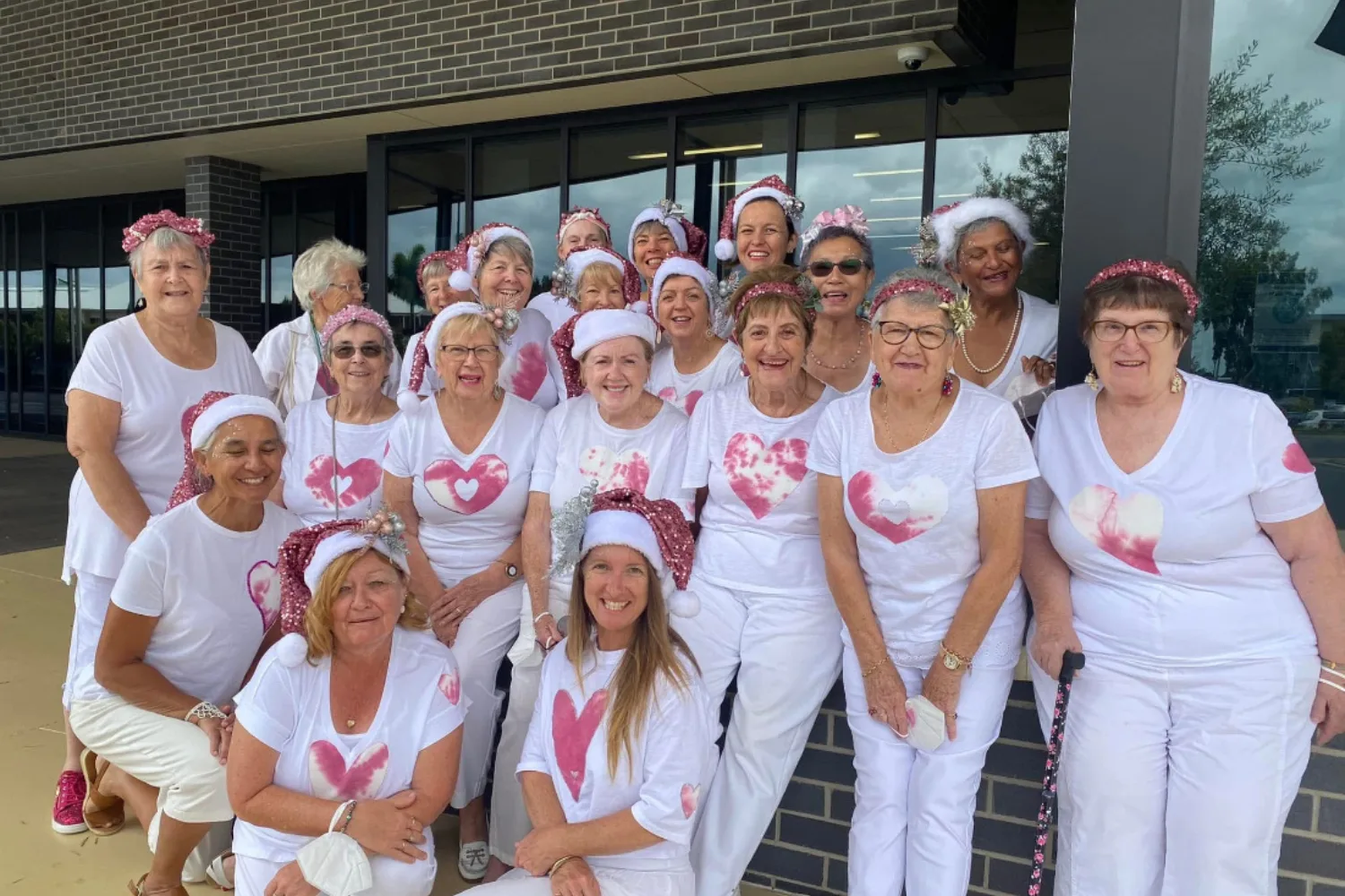 Image of women wearing white shirts and pink hats for breast cancer awareness