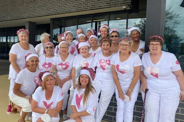 Image of women wearing white shirts and pink hats for breast cancer awareness