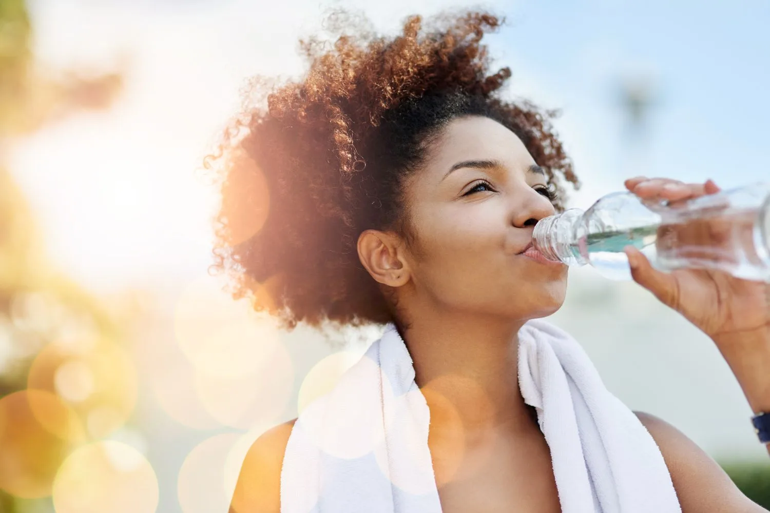 Woman outside drinking from a plastic water bottle