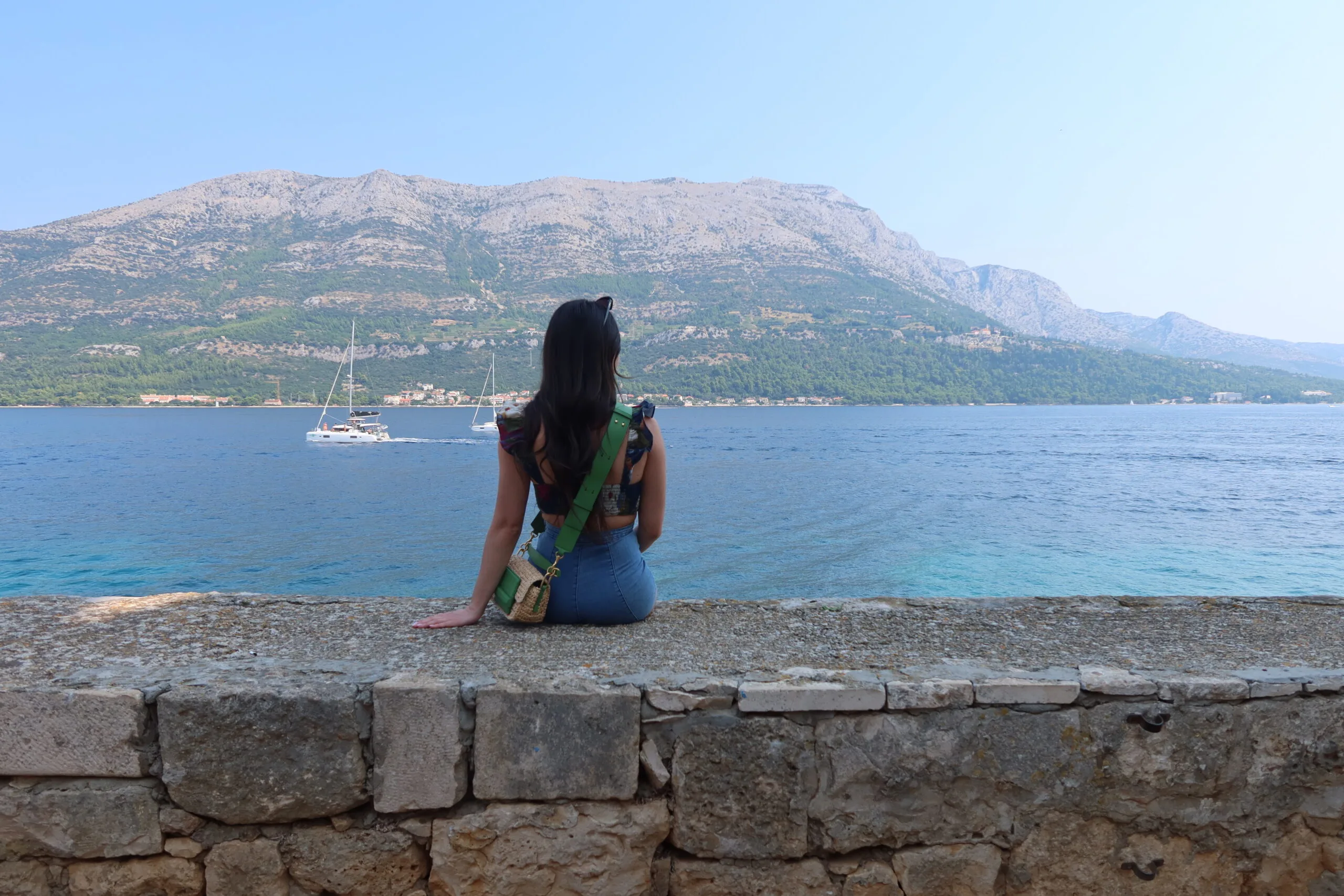 Image of girl sitting infront of view in Korcula town