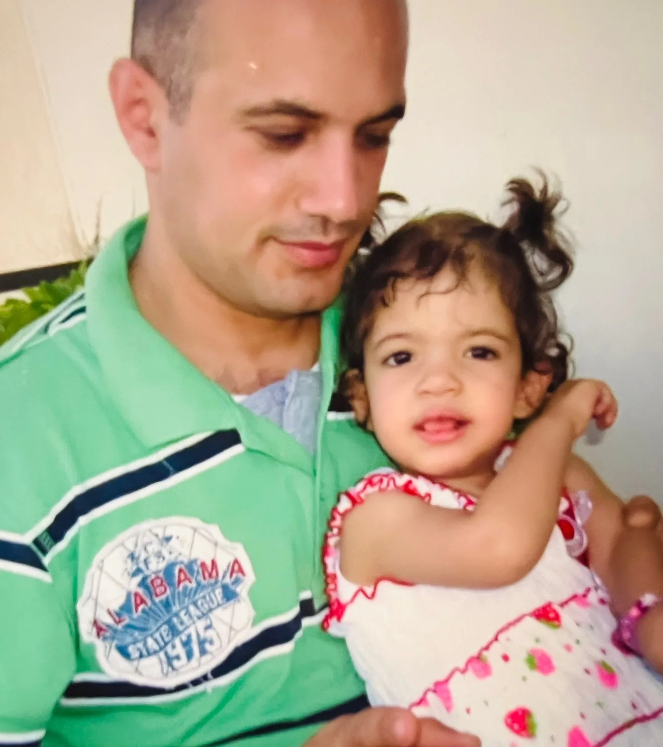 dad in green shirt holding young daughter