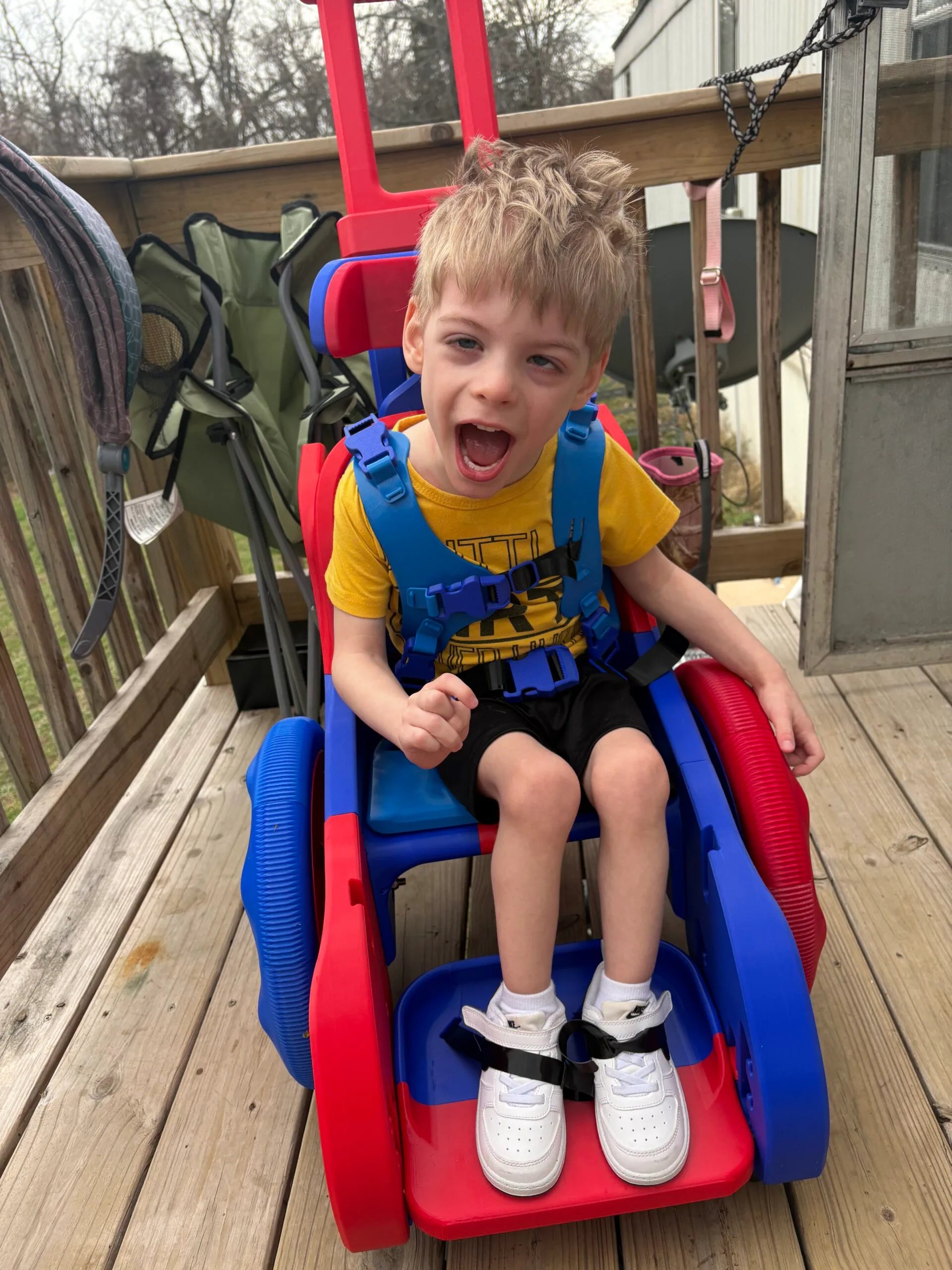 Little boy in a red and blue 3D printed wheelchair.