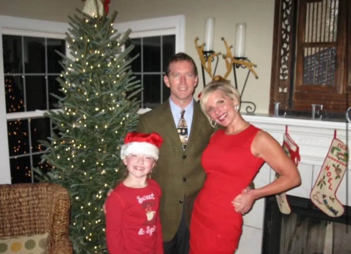 man and woman by christmas tree with young girl