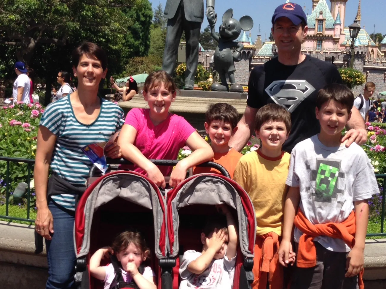 Man, woman and 6 children all smiling infront of Disney Land.