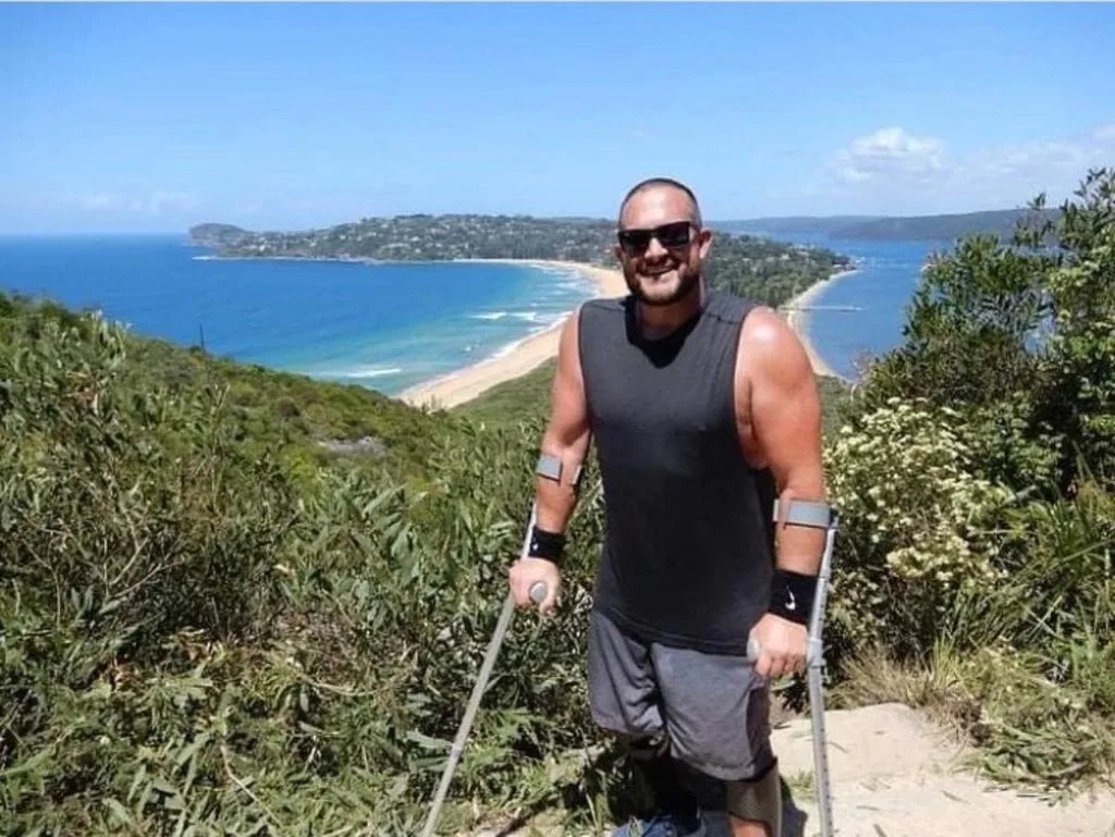 Image of paraplegic man walking with crutches