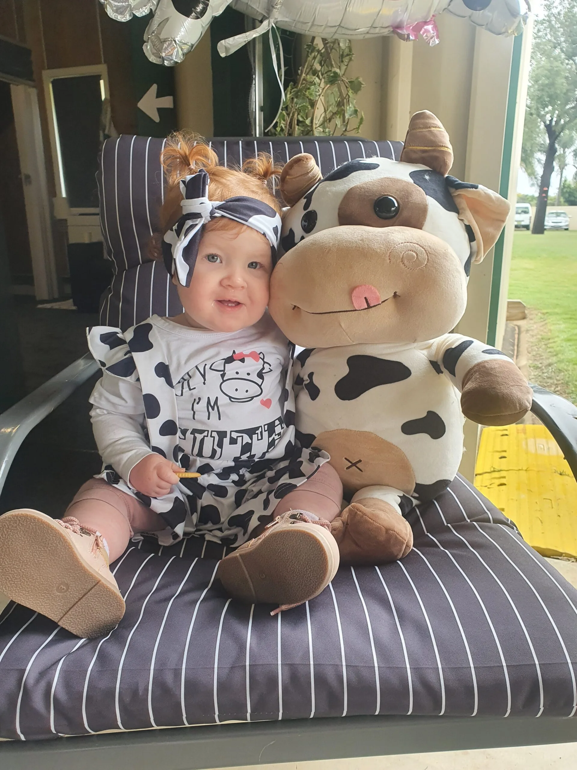 Image of little girl smiling with plush cow toy