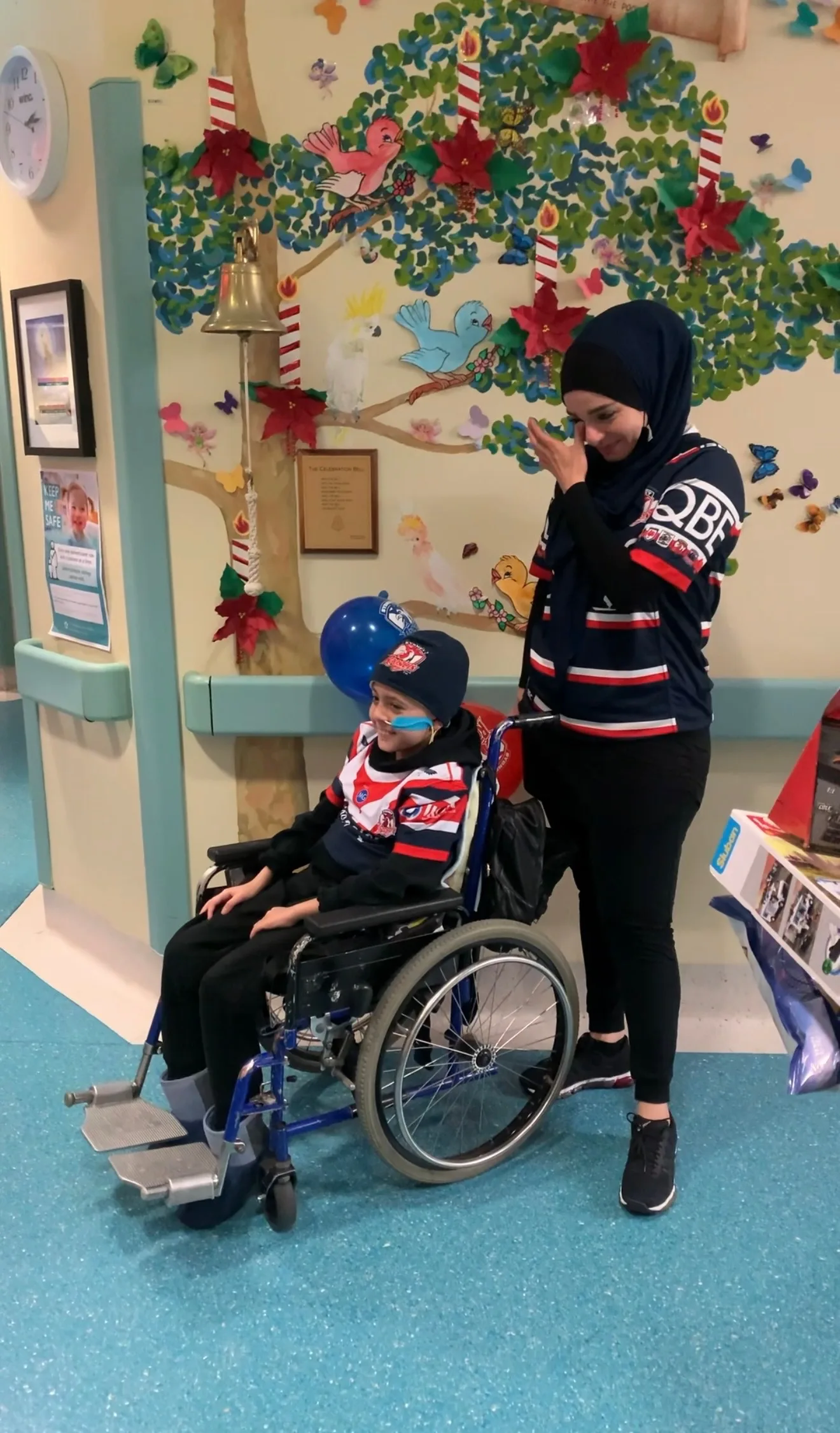 woman wiping tear, son ringing bell from wheelchair