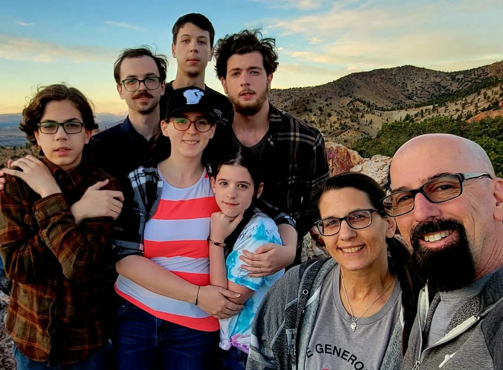 Family photo of woman and man smiling next to each other with their adult kids.