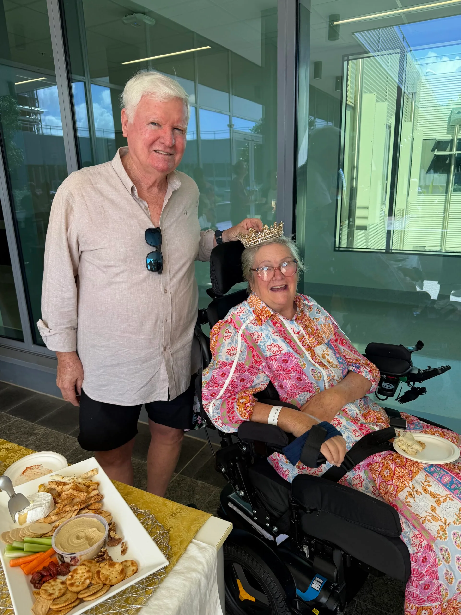 woman in wheelchair wearing crown, man behind her