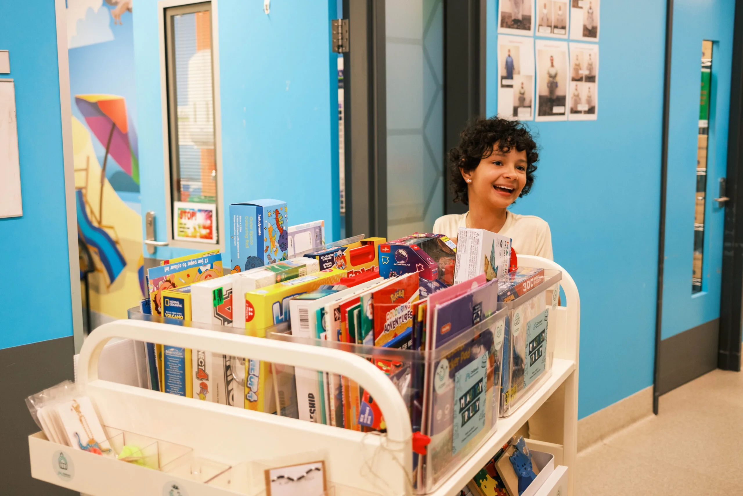 girl pushing trolley full of books and toys