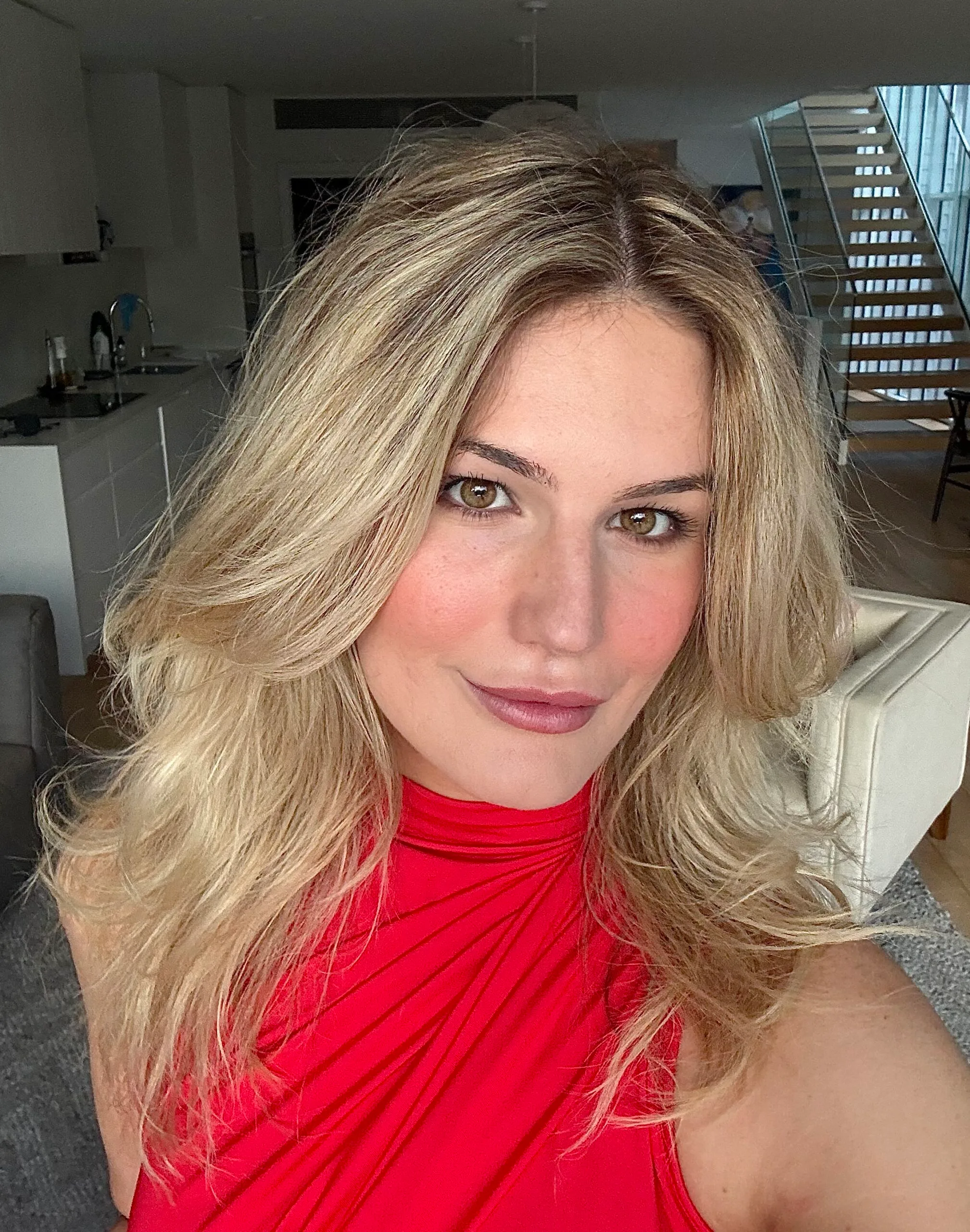 Woman with blonde hair, wearing red shirt and looking at camera.