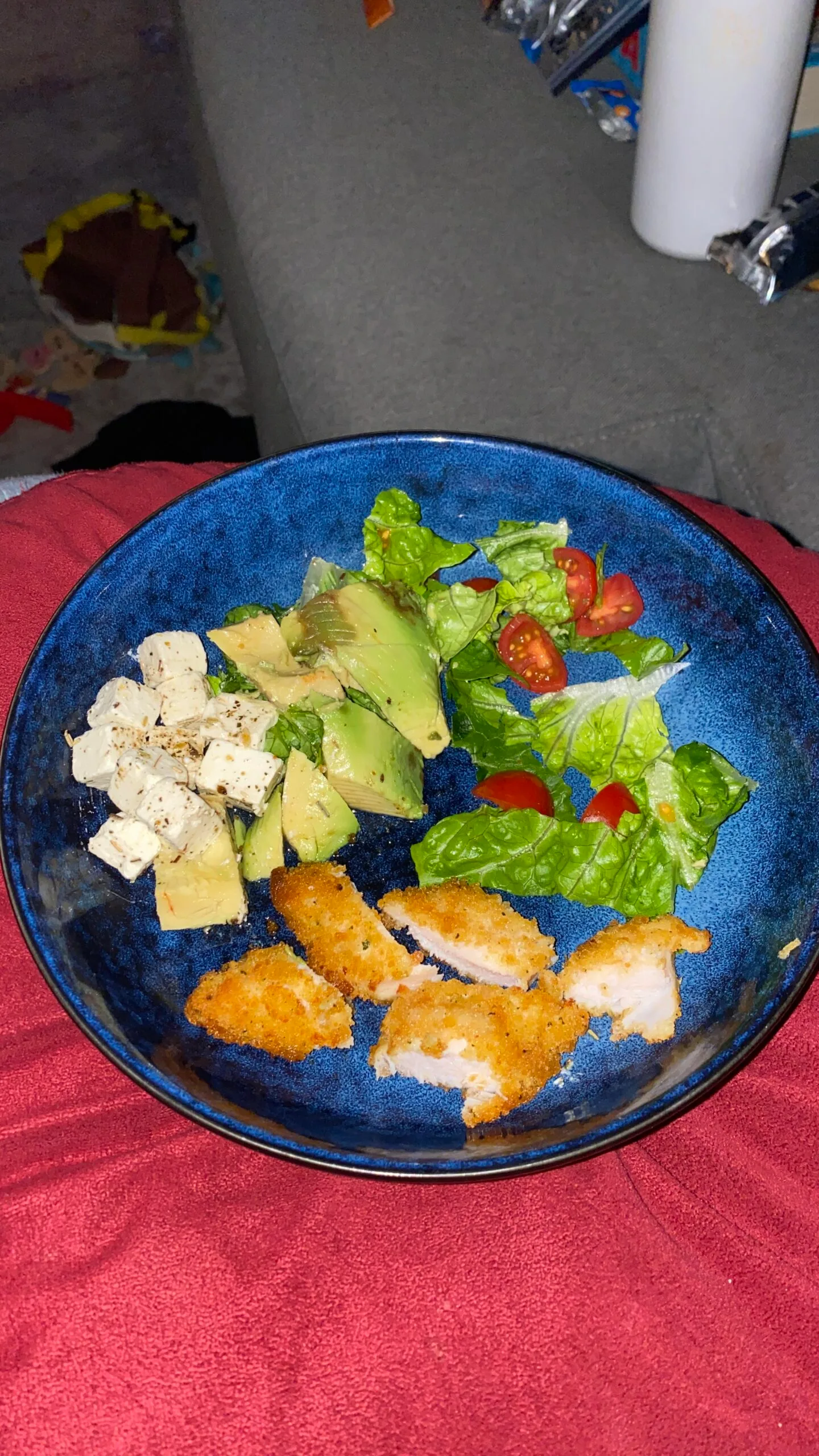 Bowl of avocado, feta cheese and crumbed chicken.
