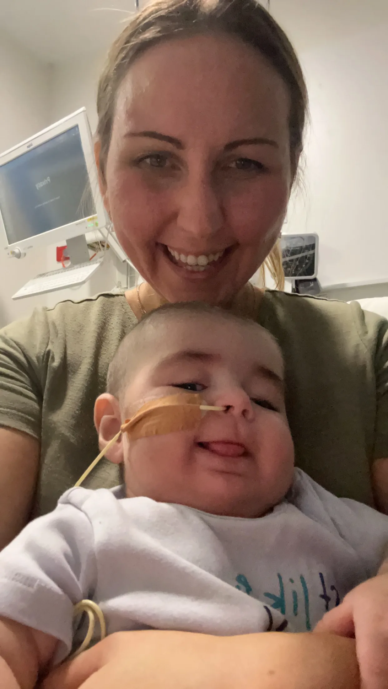 Woman and toddler with feeding tube smiling at camera.