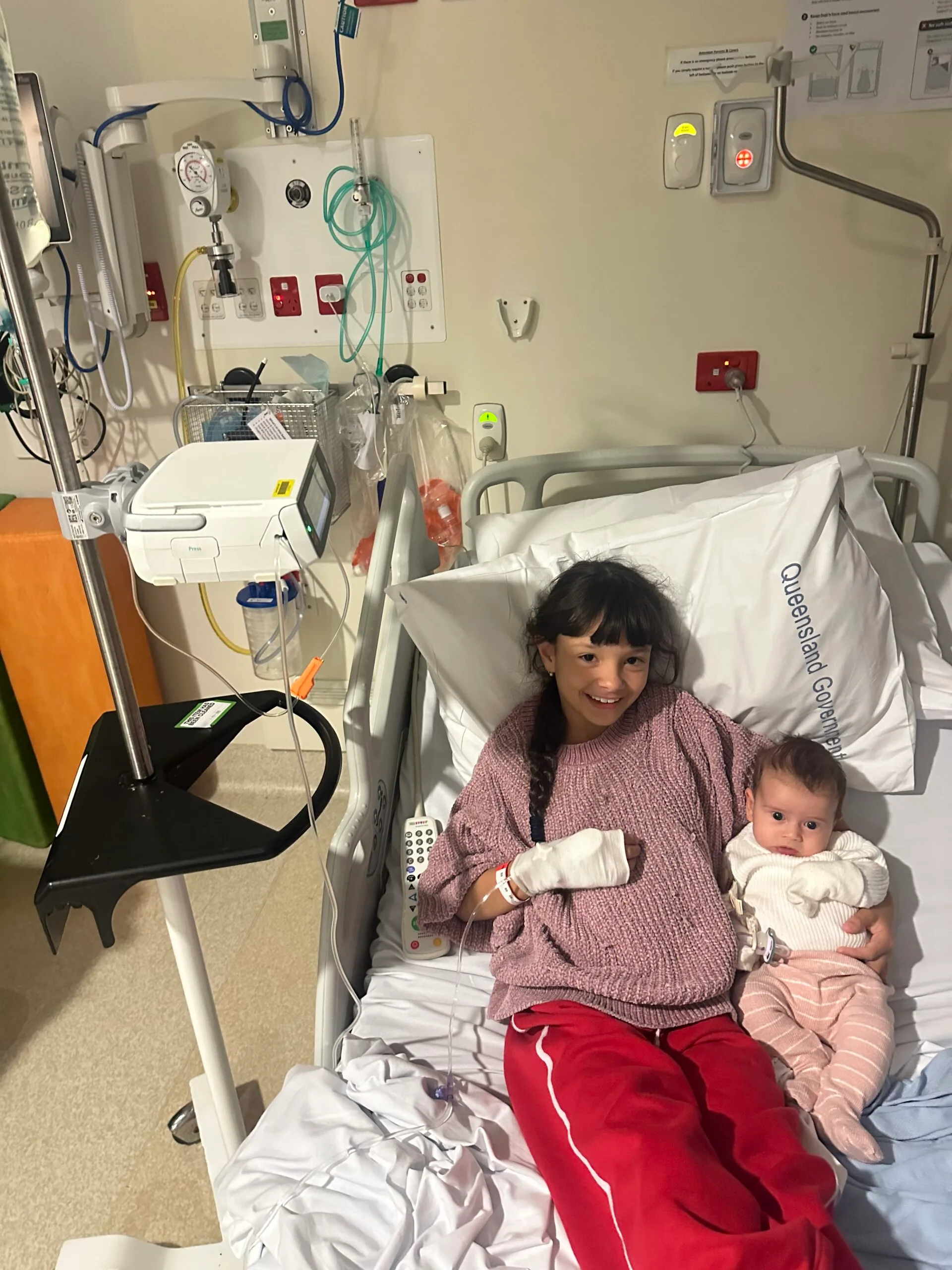 girl cuddling baby in hospital bed
