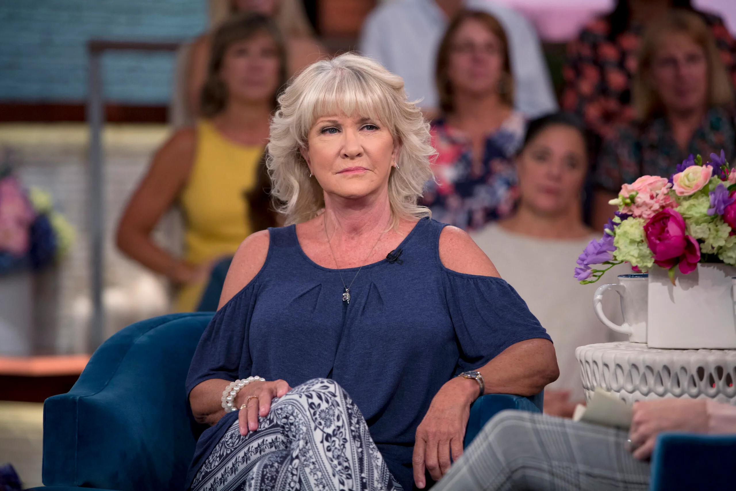 Woman with blonde hair, wearing blue top on a talk show.