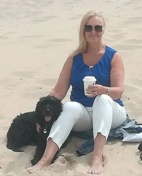 Image of woman and black dog sitting on the beach