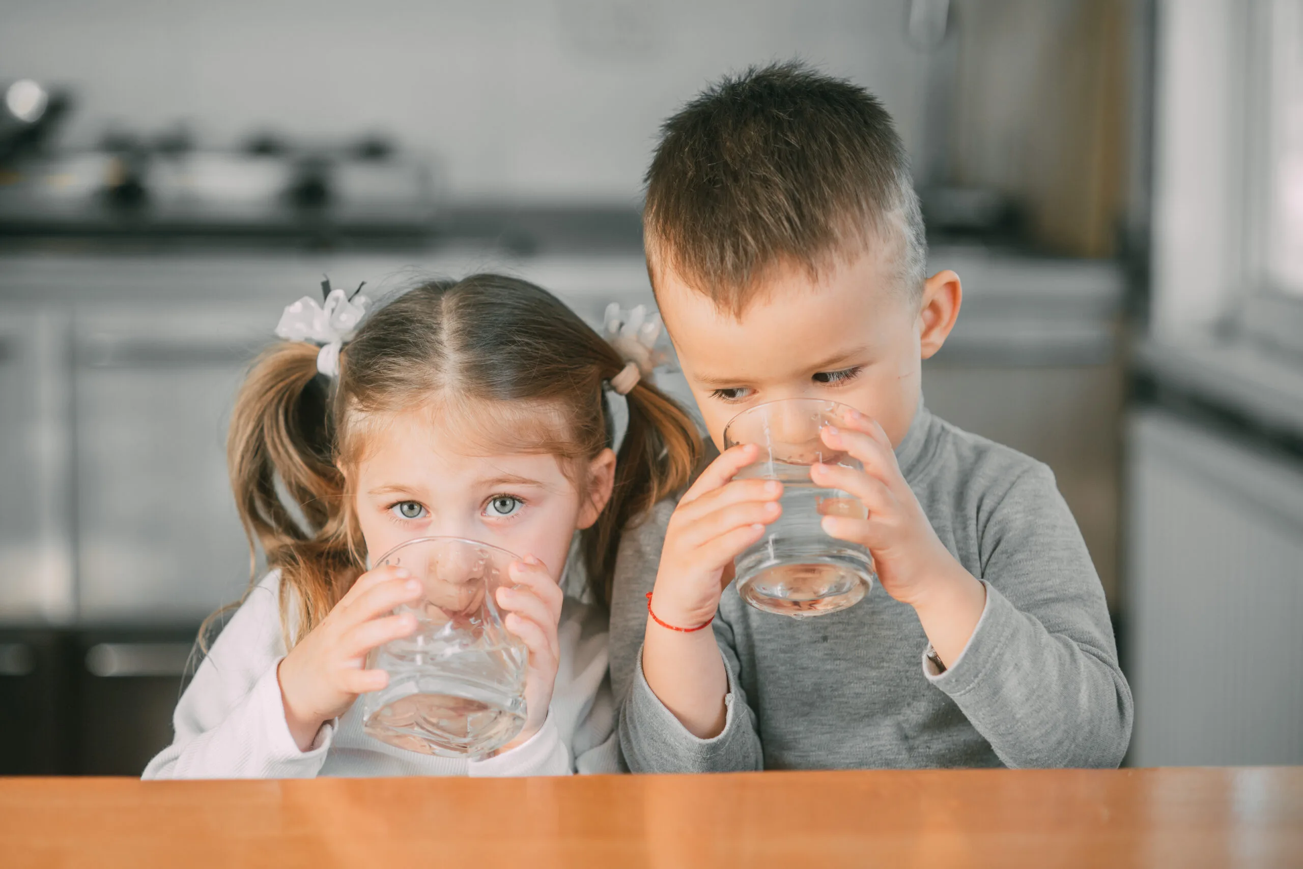 Young girl and boy drinking water.