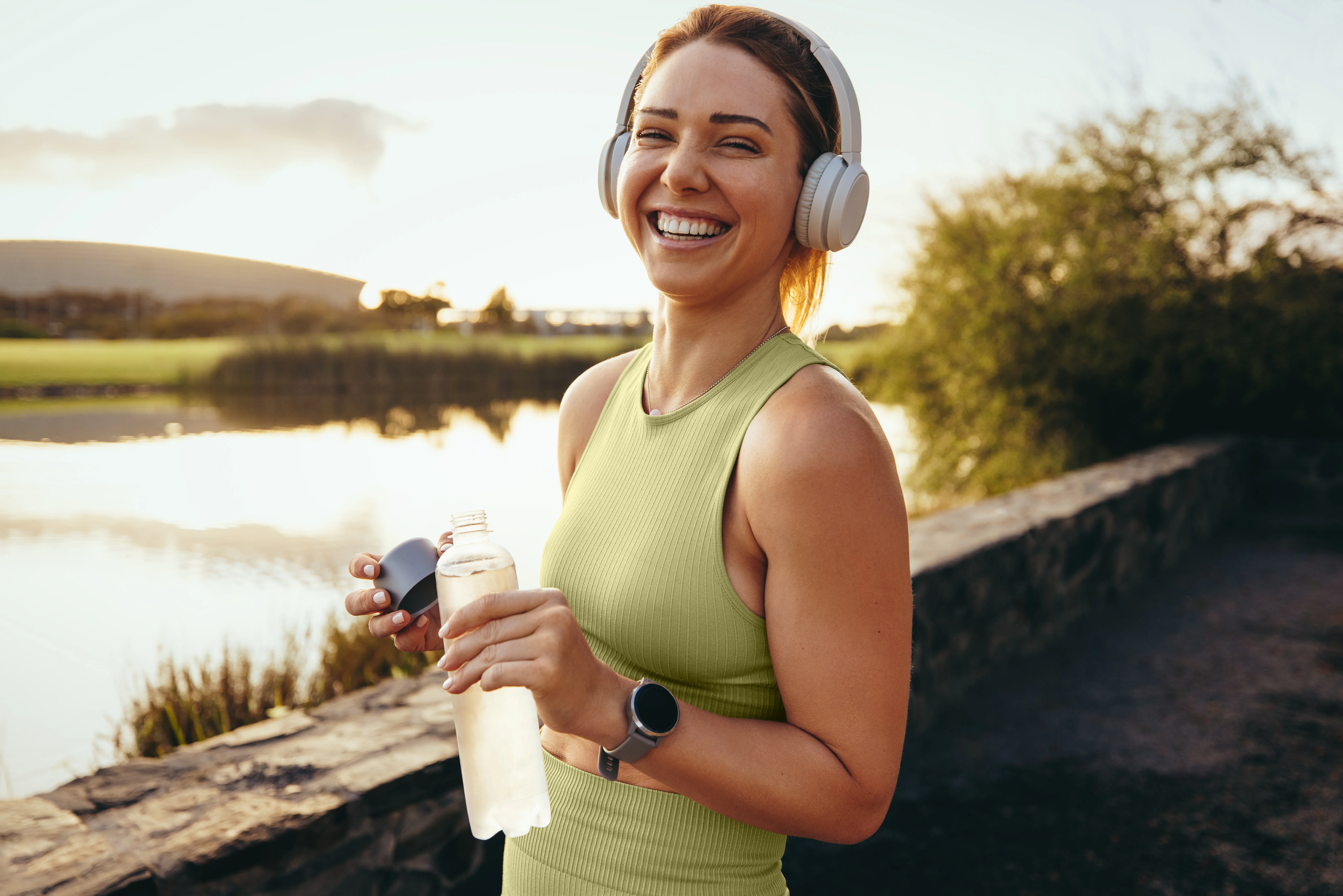 Woman wearing sports outfit holding cold bottle of water.