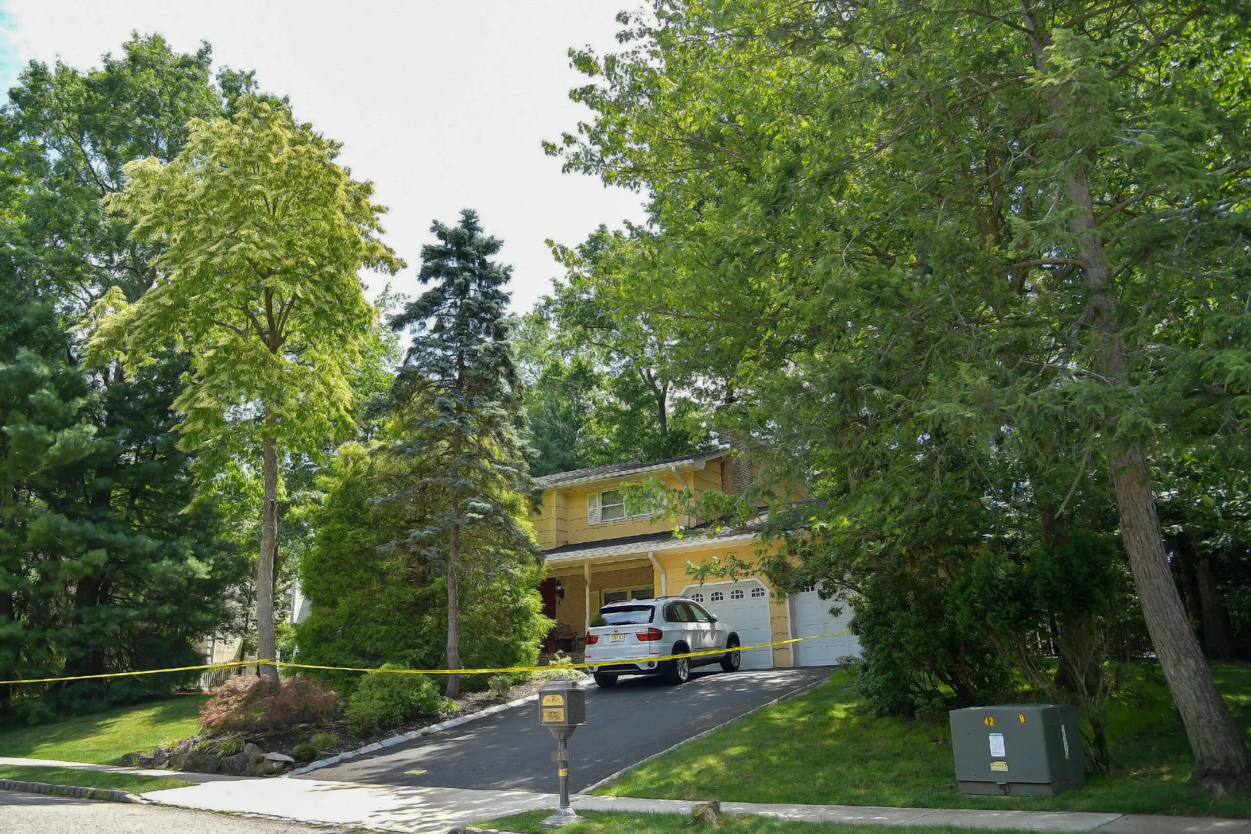 Photo of house, with car in the driveway that's been barricaded with police tape.