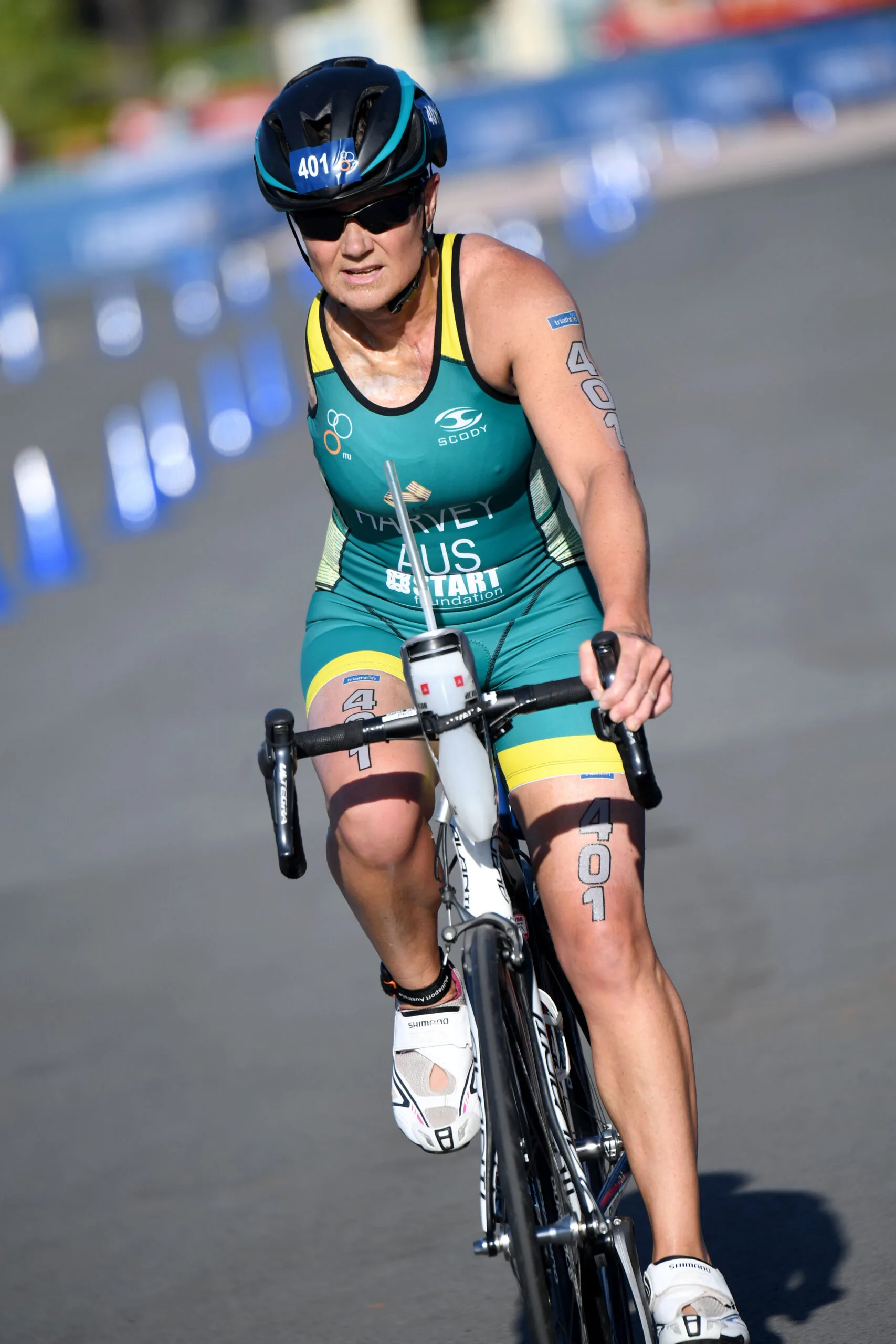 Woman with arm, wearing helmet and sunglasses on pushbike, biking down a track.
