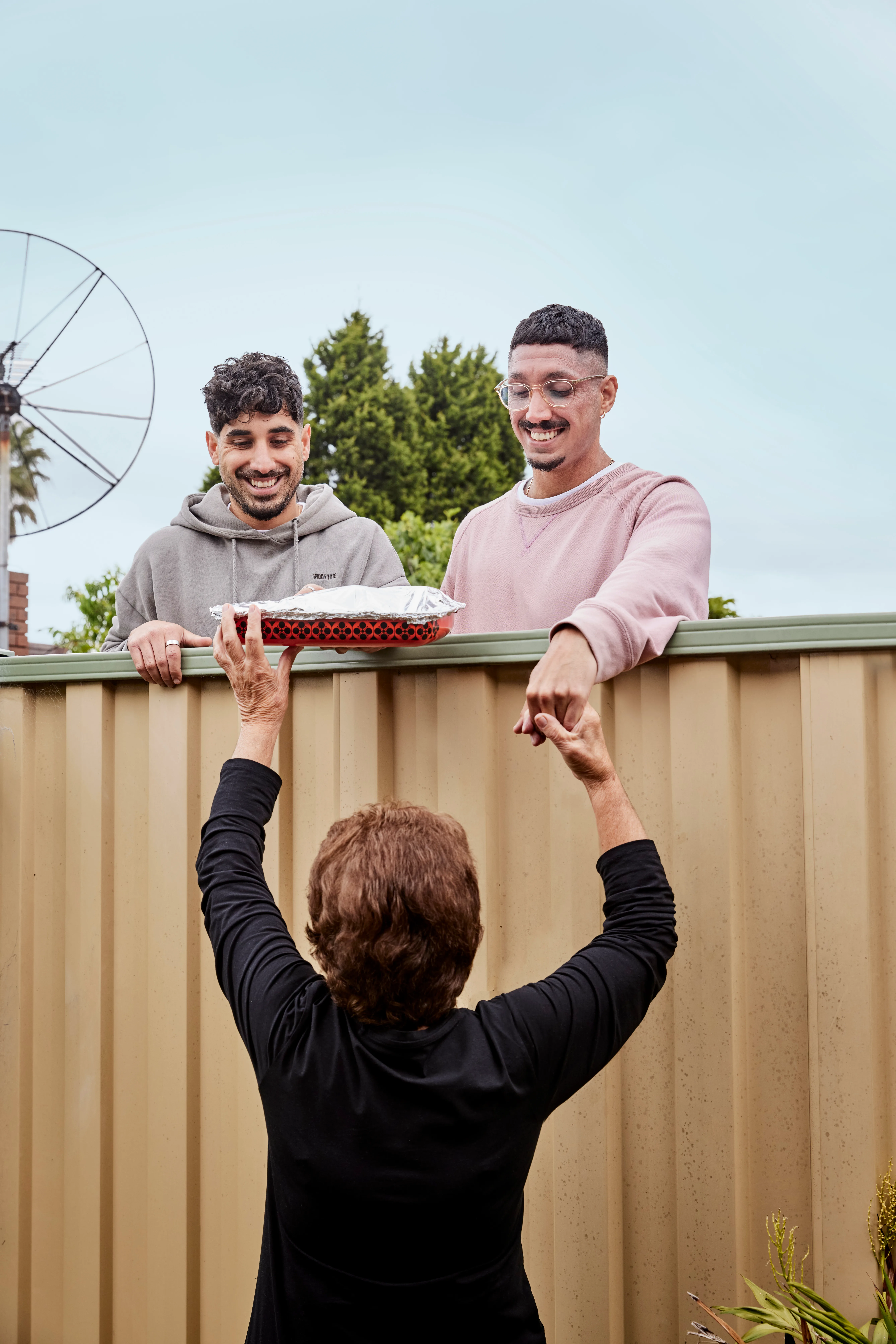 brothers collecting meal over the fence from older woman