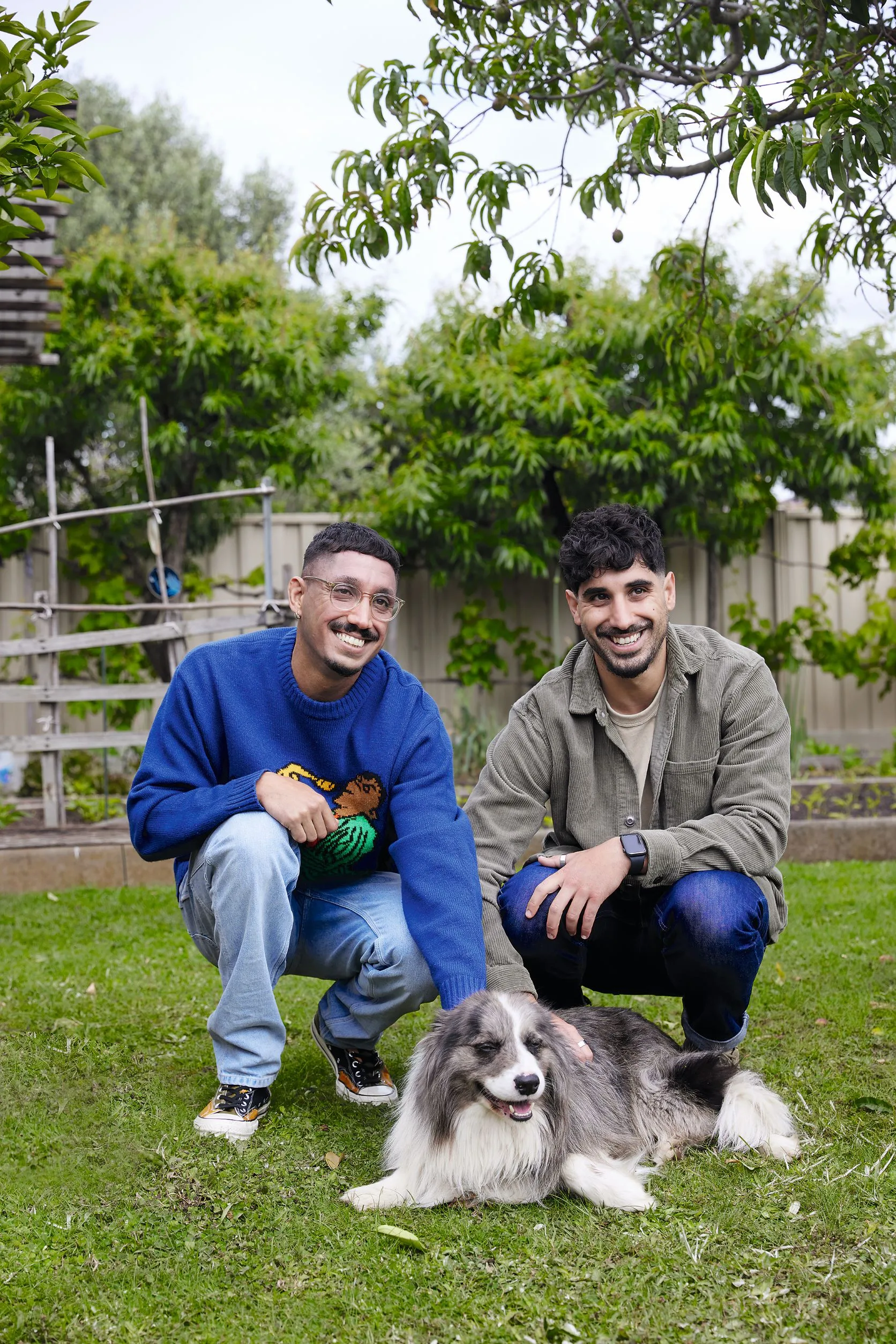 brother in blue shirt and man in kahki shirt patting dog