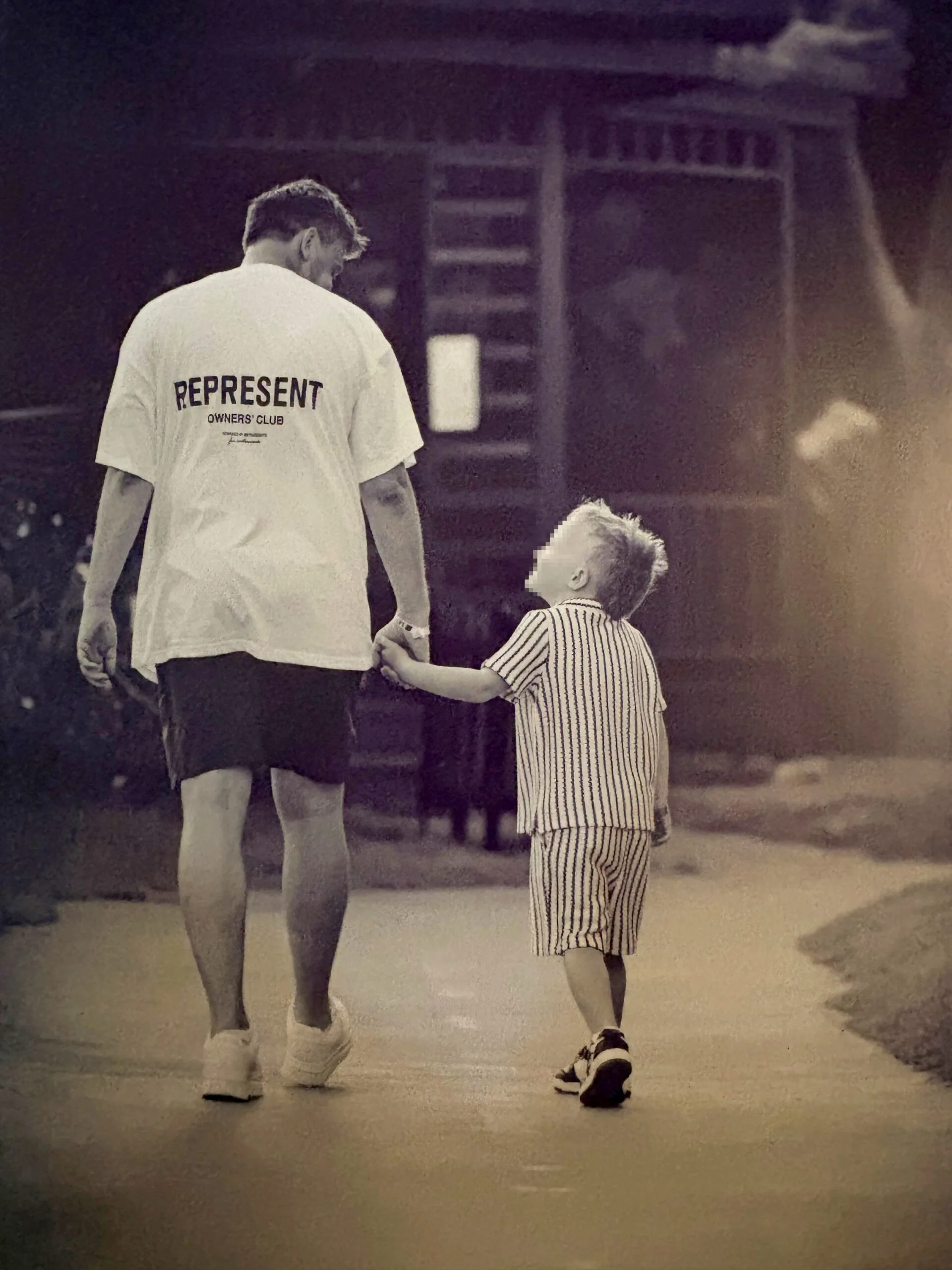 man and son walking hand in hand backs to camera
