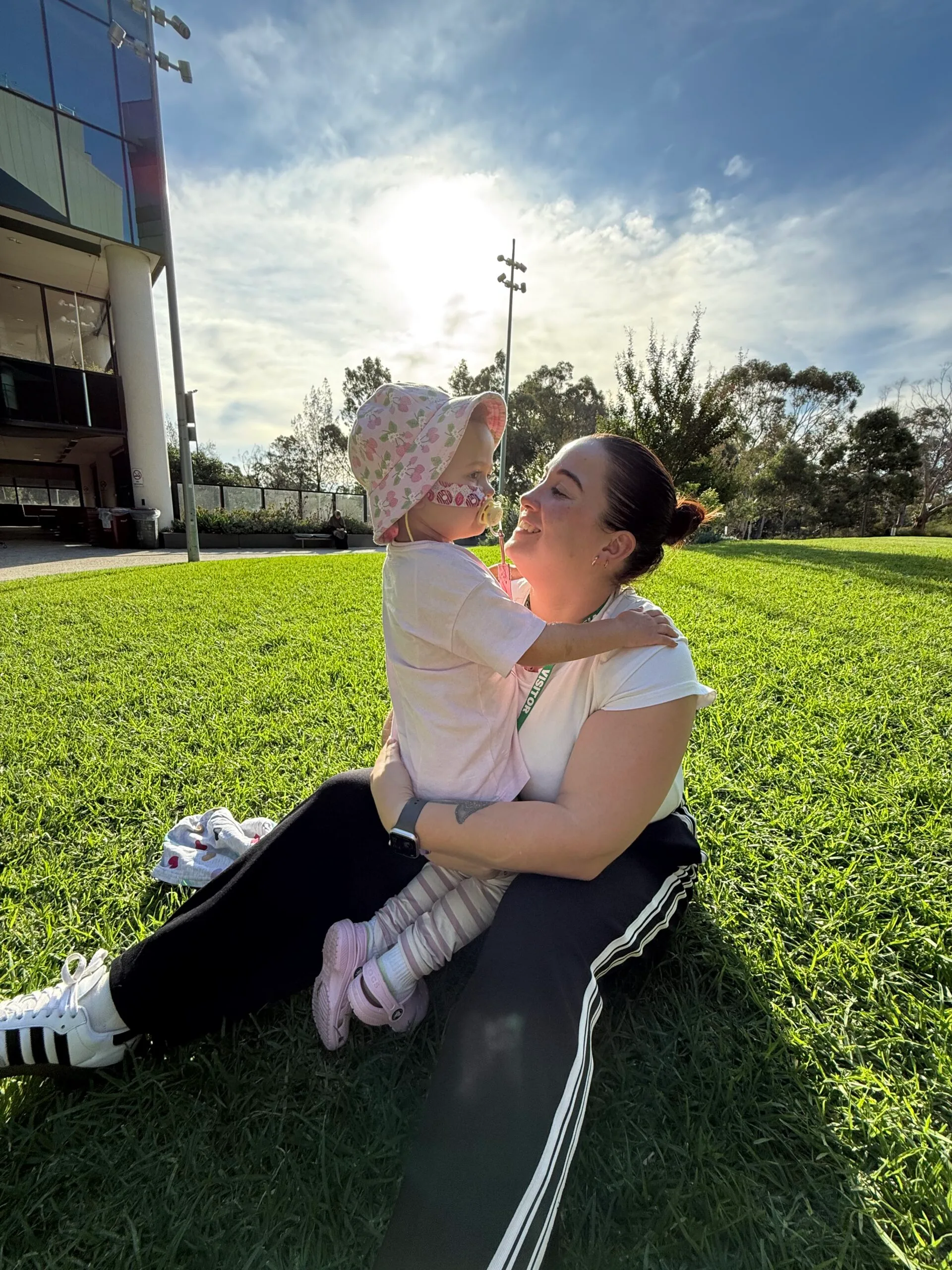 mum and daughter cuddle in grass 