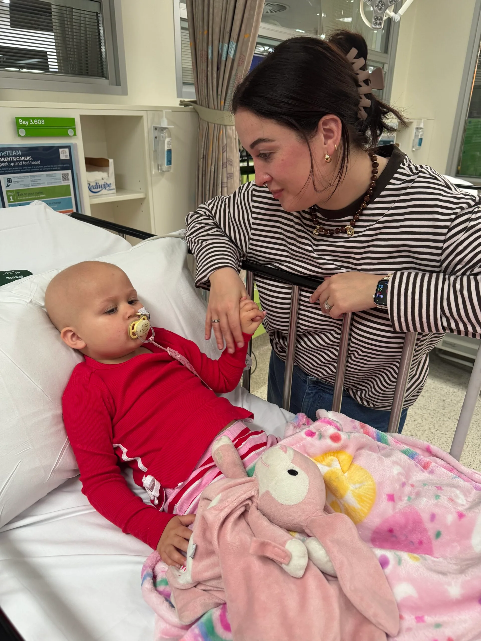 mum holding sick daughters hand in hospital 
