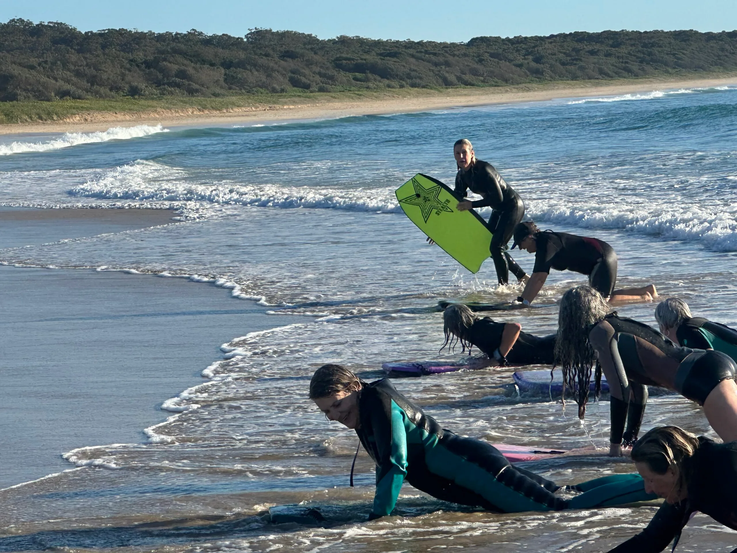 Women setting up surf boards to get into the ocean.