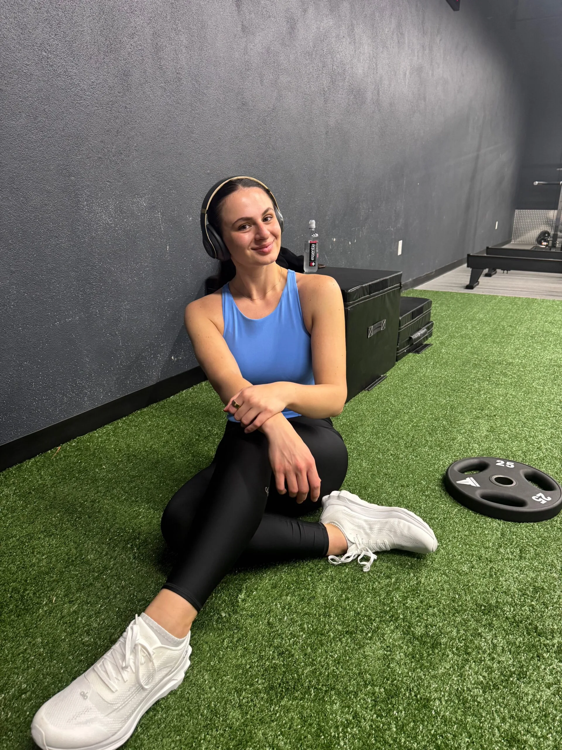 Woman wearing gym clothing sitting on the ground at the gym.