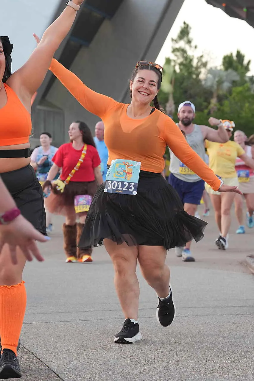 woman in orange top and black skirt running