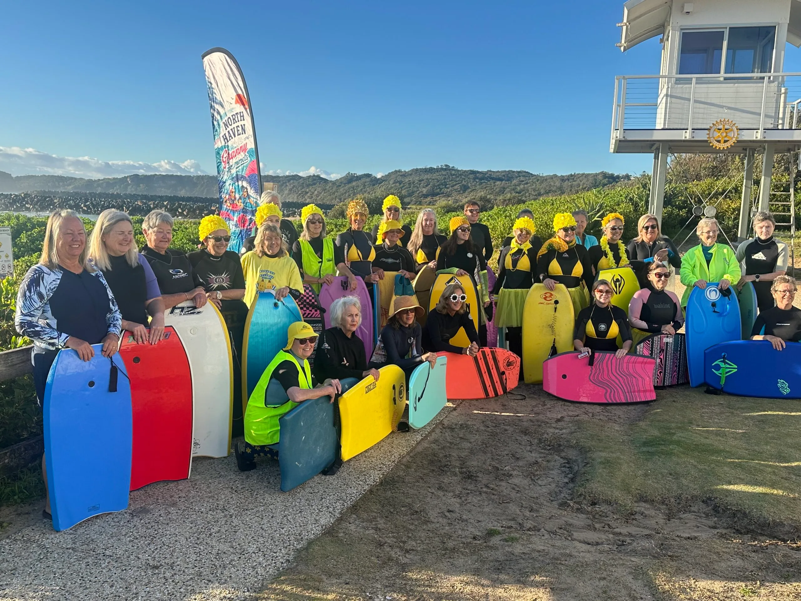 Large group of women holding surfboards and smiling at camera.