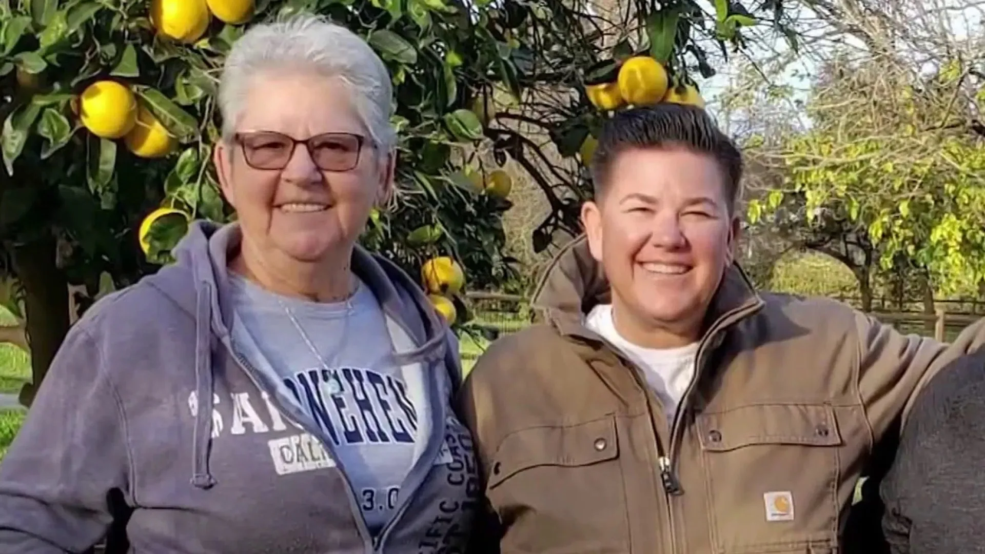Elderly woman with short hair smiling next to younger lady.