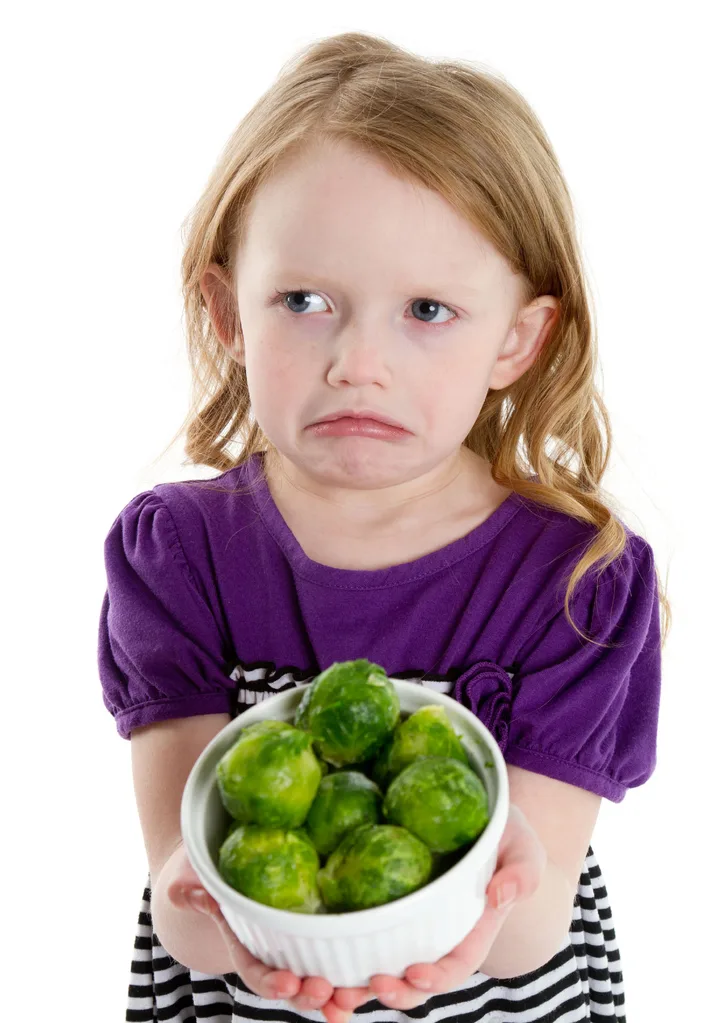 Girl looking disgusted with bowl of Brussels sprouts