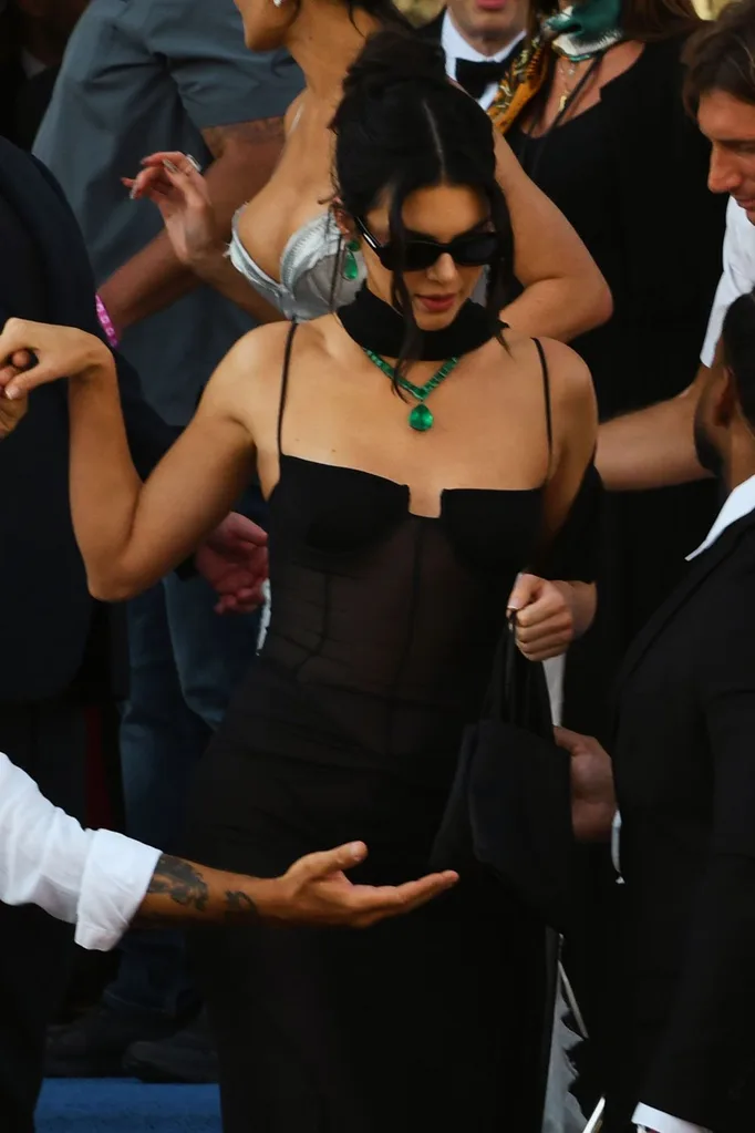 Kendall Jenner in an all black dress stepping onto a boat.