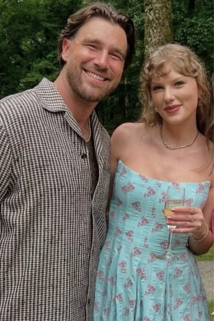 Taylor Swift in a Blue wedding Guest Dress next to Travis Kelce.